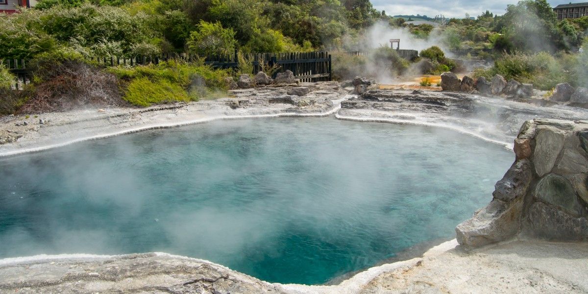A steaming turquoise hot spring surrounded by rocks and vegetation. Portugal hot springs