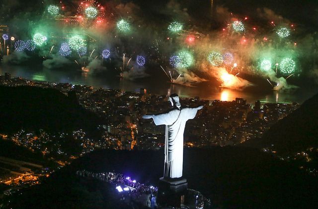 Fireworks over Christ the Redeemer statue in Rio de Janeiro, Brazil. City lights below, night sky.