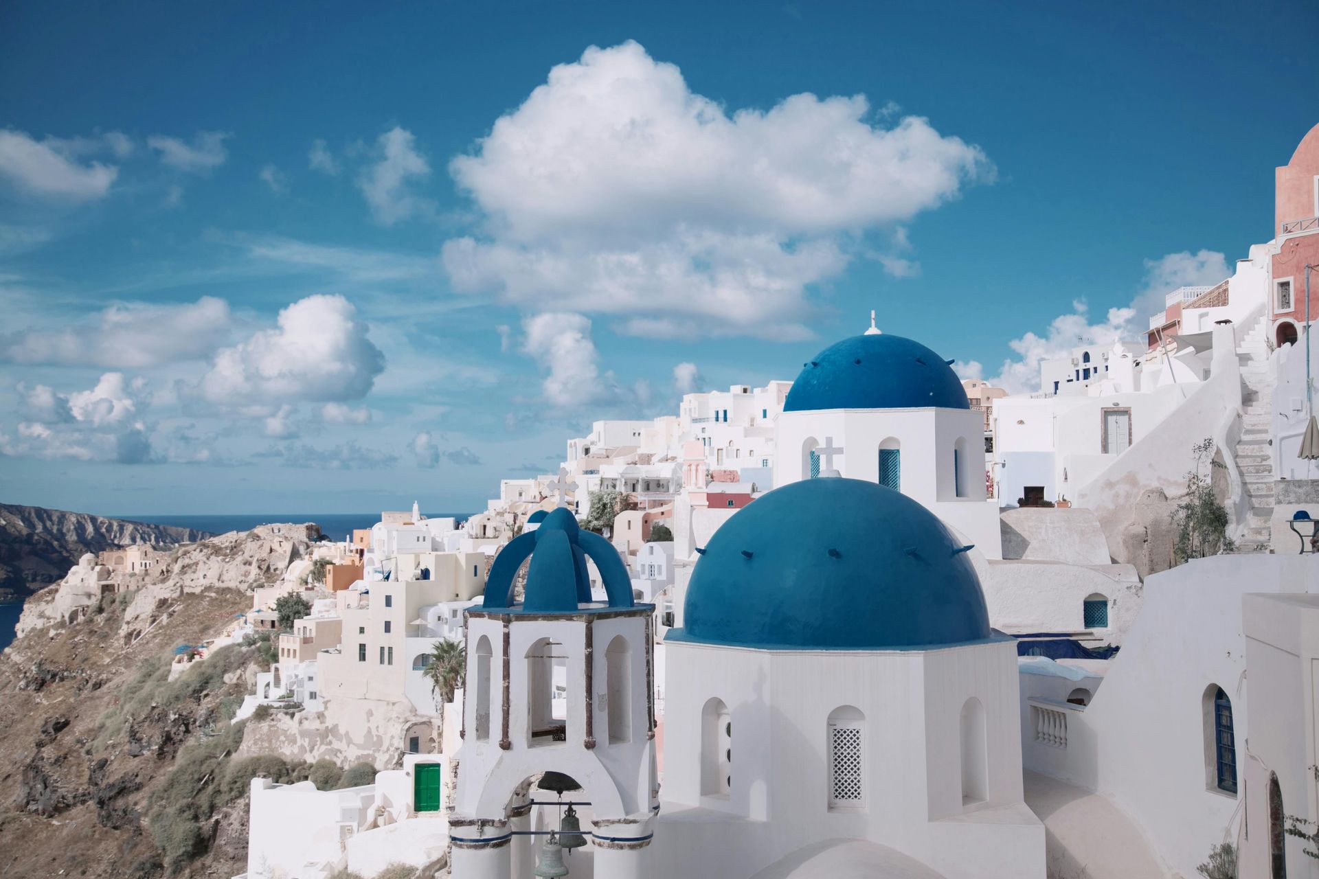 White buildings with blue domes in Santorini, Greece, against a blue sky with clouds. santorini