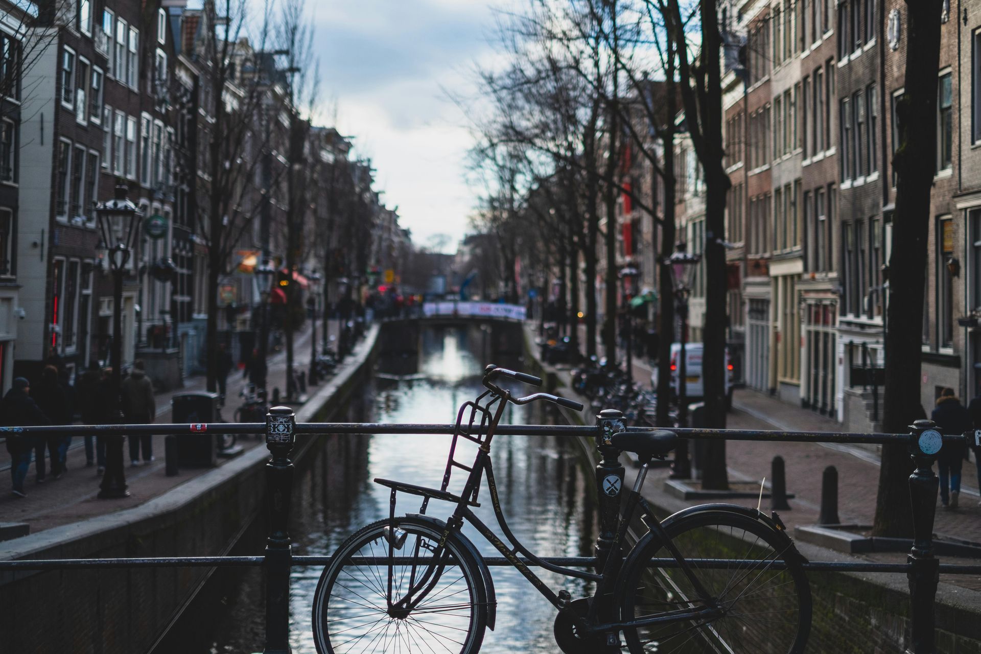 Amsterdam canal scene: a bicycle parked on a bridge with buildings lining the water, overcast day.