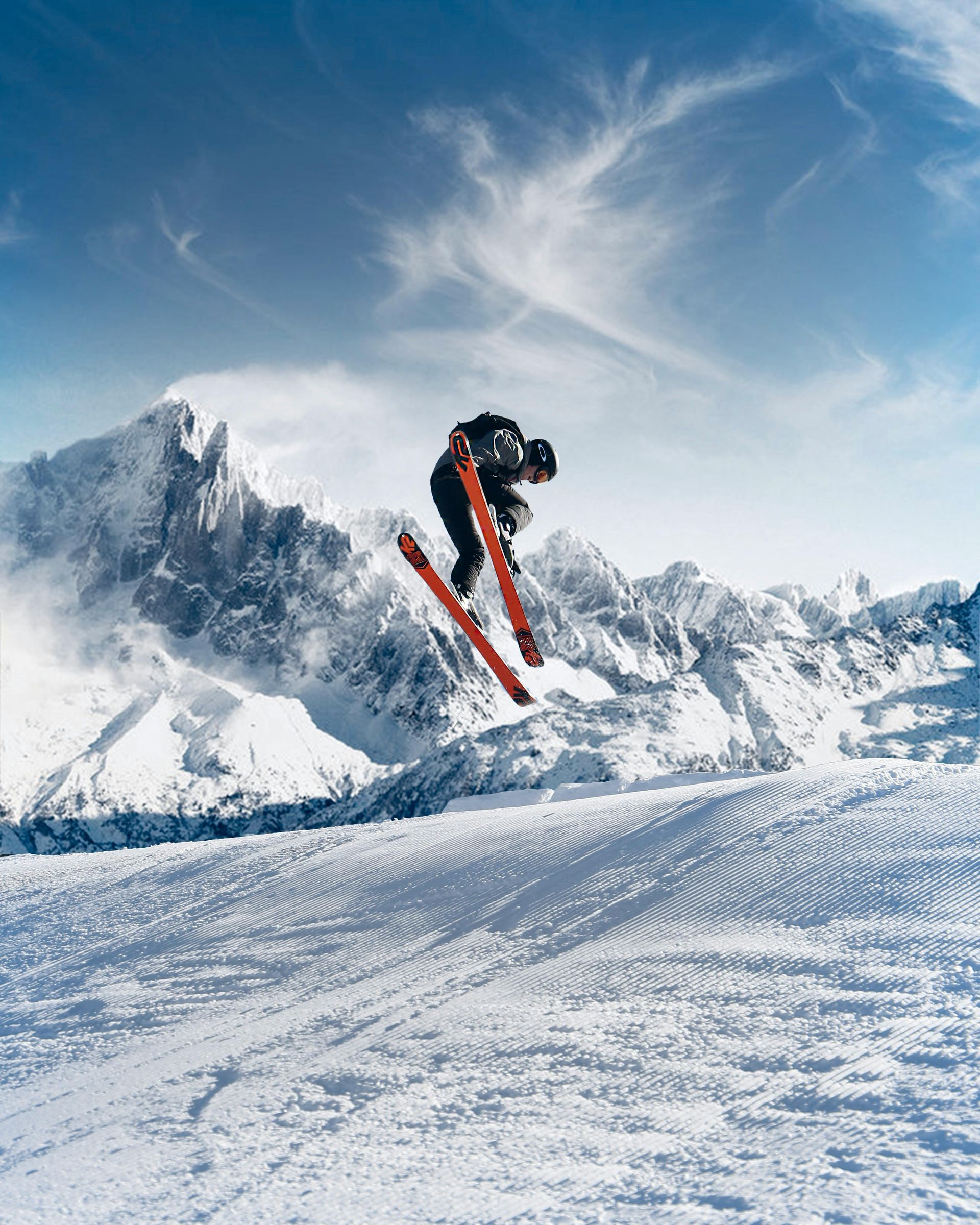 Skier jumps in mid-air on a snowy slope with mountain backdrop and a bright blue sky. Canada: Wilderness on a Grand Scale