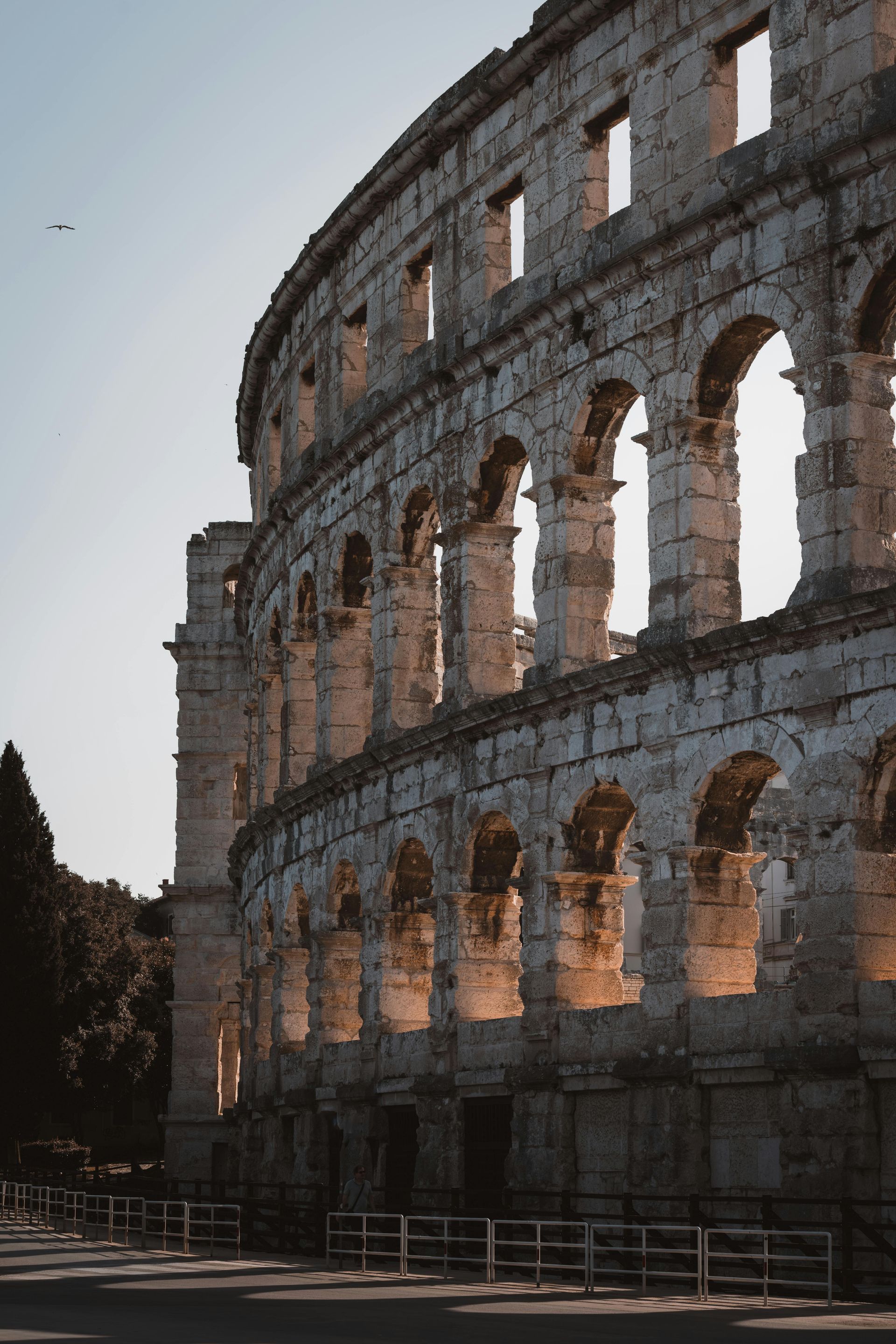 Roman amphitheater exterior, stone arches and columns, bathed in warm sunlight. Istria, Croatia