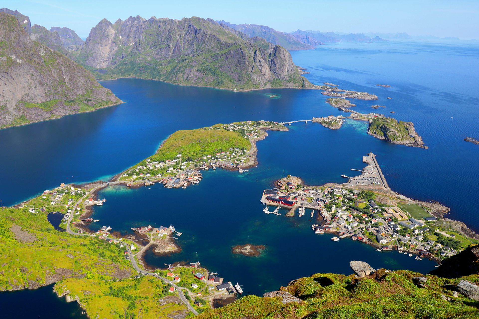 An aerial view of a coastal village with colorful houses, bridges, and mountains in Norway. Northern Norway