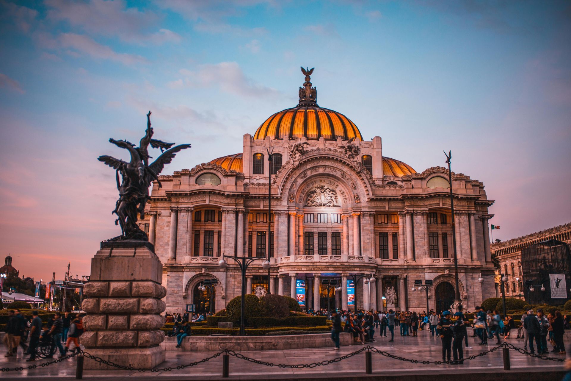 Palacio de Bellas Artes, Mexico City, exterior view at dusk, with sculptures, dome, and people.