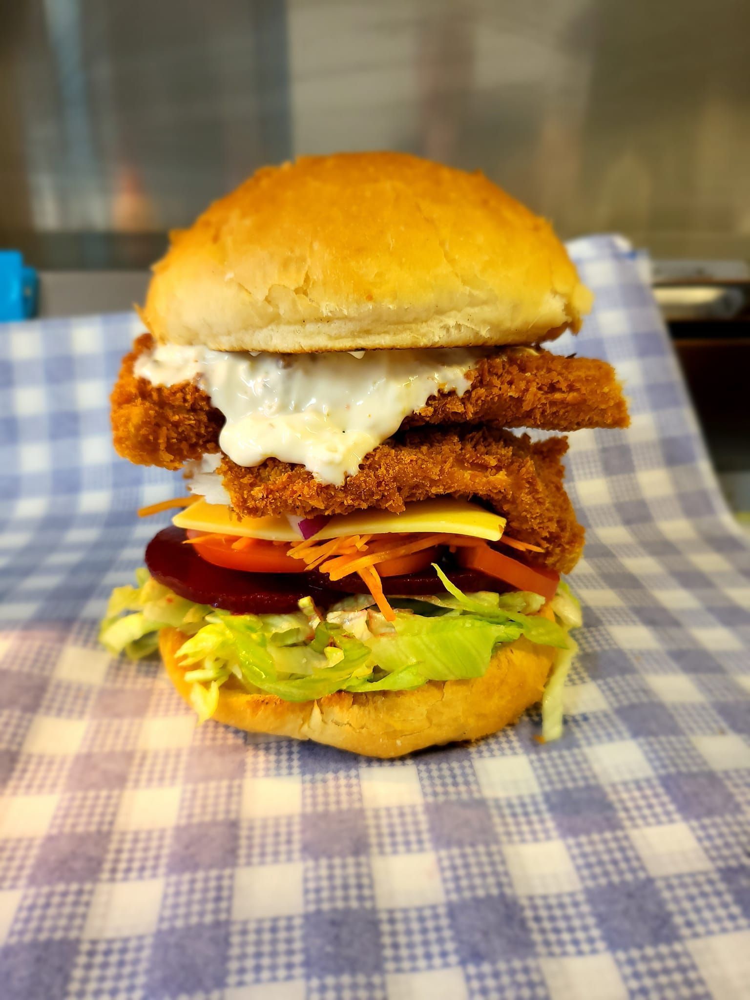 A Layered Burger With a Breaded Patty, Cheese, and Vegetables — Boundary Street Fish & Burger Bar in Railway Estate, QLD