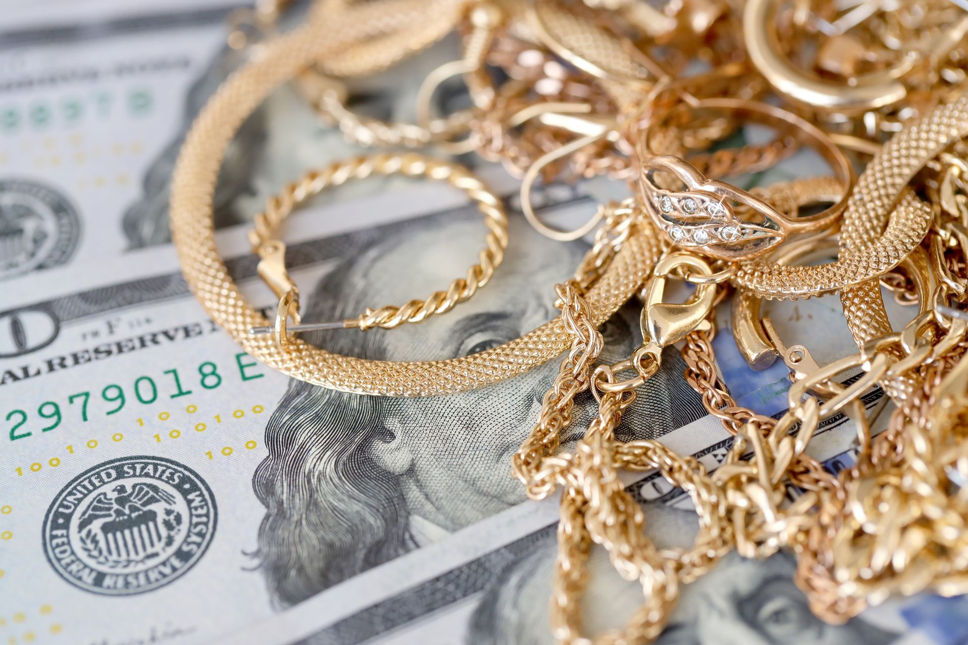 A pile of gold jewelry sitting on top of a pile of money.