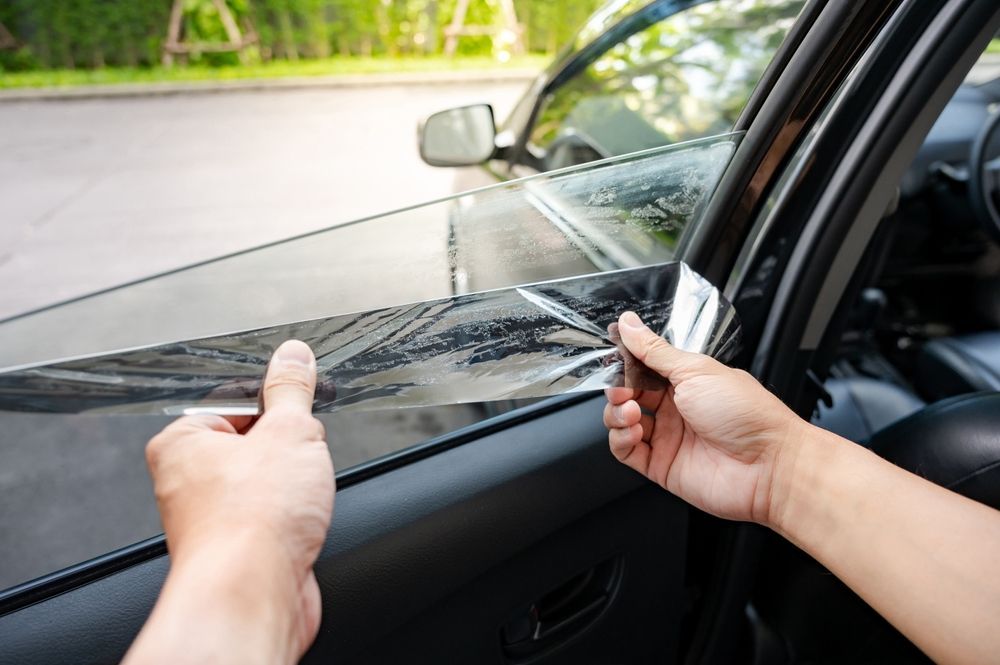 Person applying window tint to a car window.