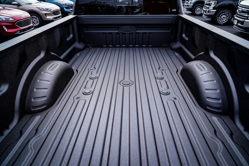 Black truck bed with textured bed liner and integrated tie-down points.
