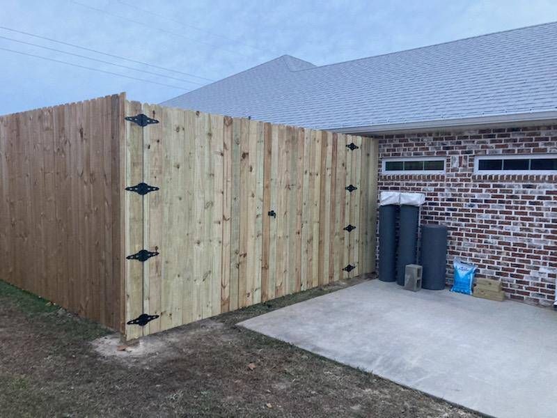 A wooden fence is in front of a brick house.
