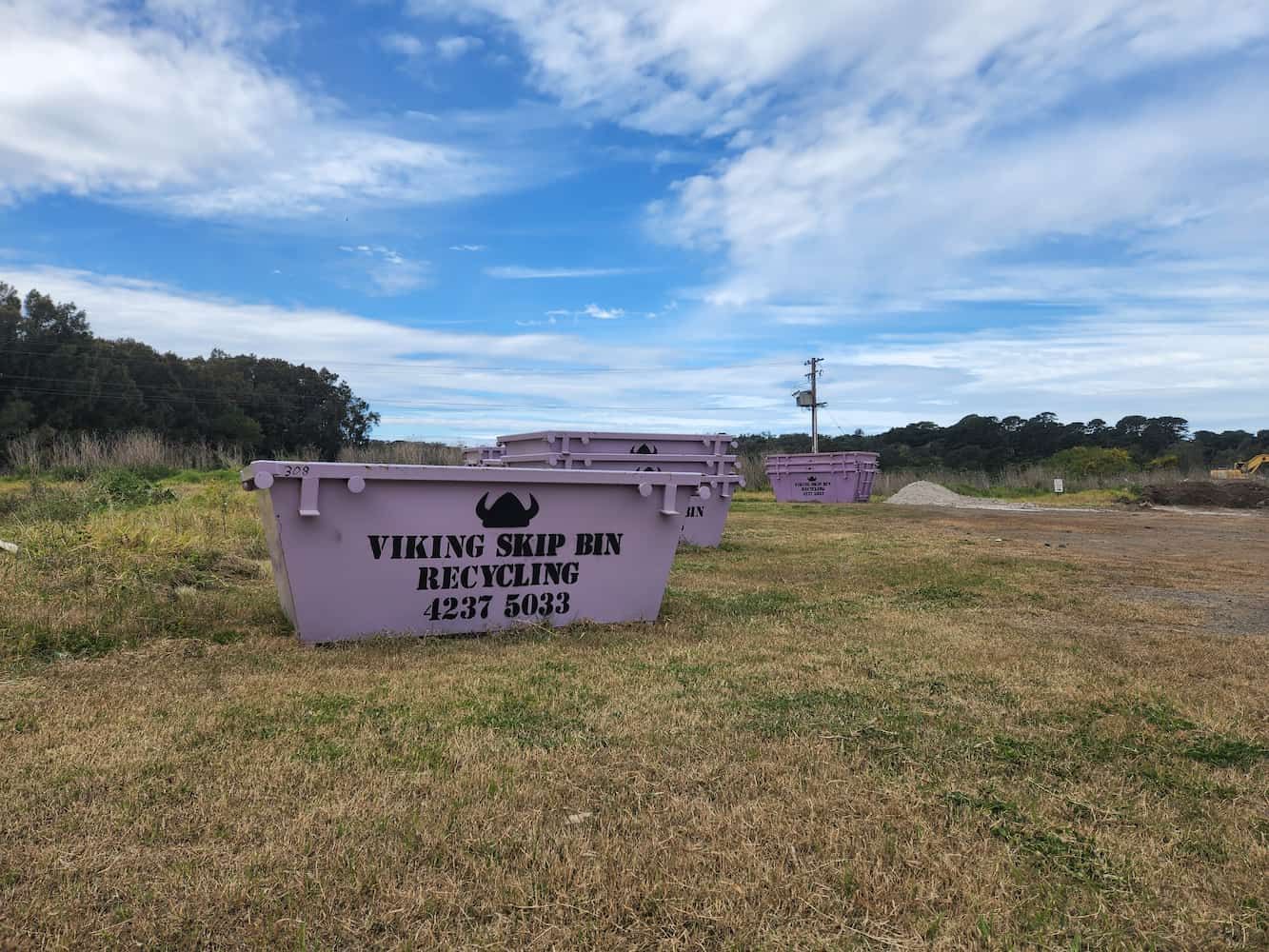 A Purple Dumpster is Sitting in the Middle of a Field — Viking Skip Bin Recycling In Bulli, NSW