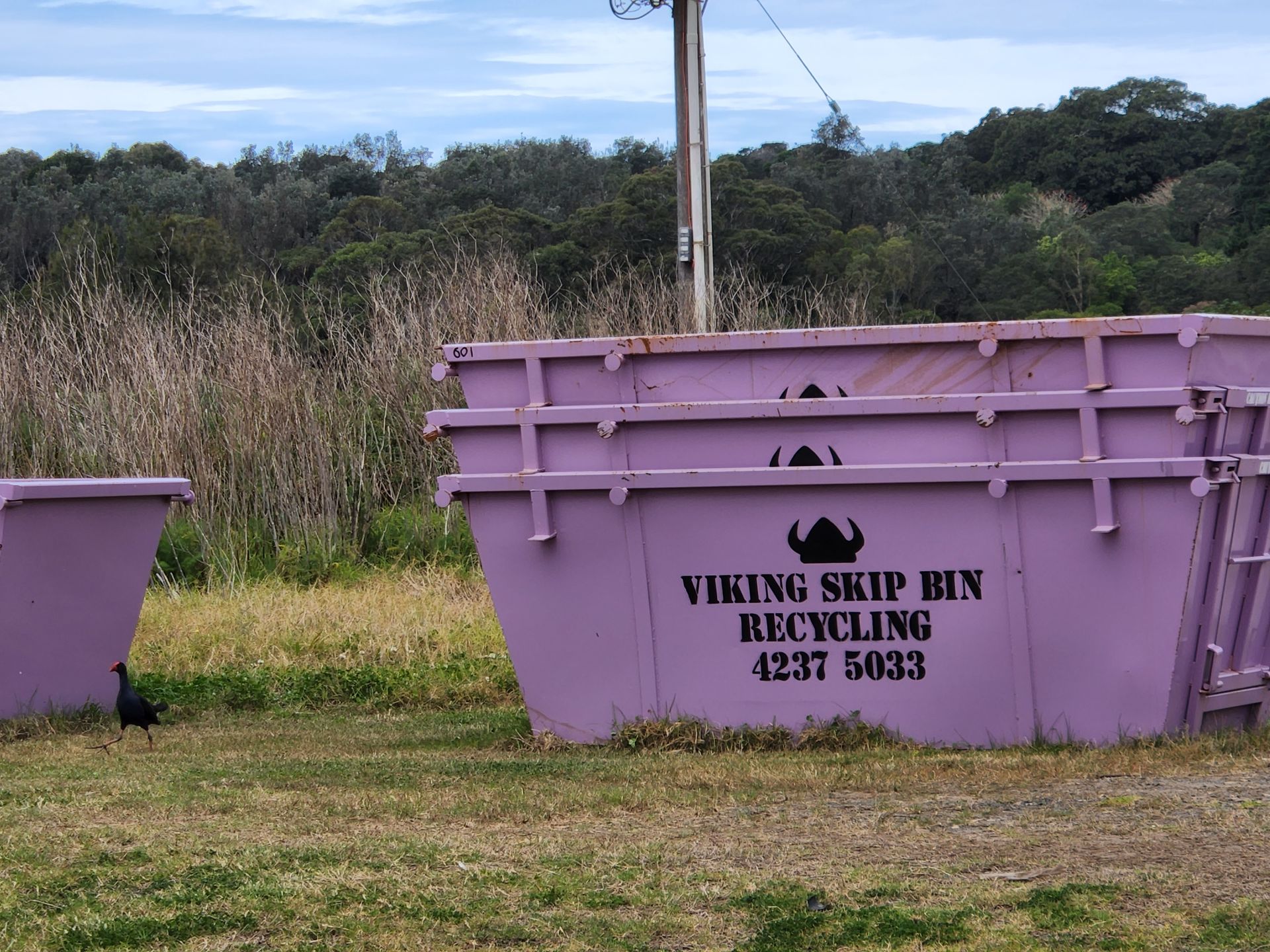 A stack of purple skip bins with viking skip bin recycling logo — Viking Skip Bin Recycling In Kiama, NSW