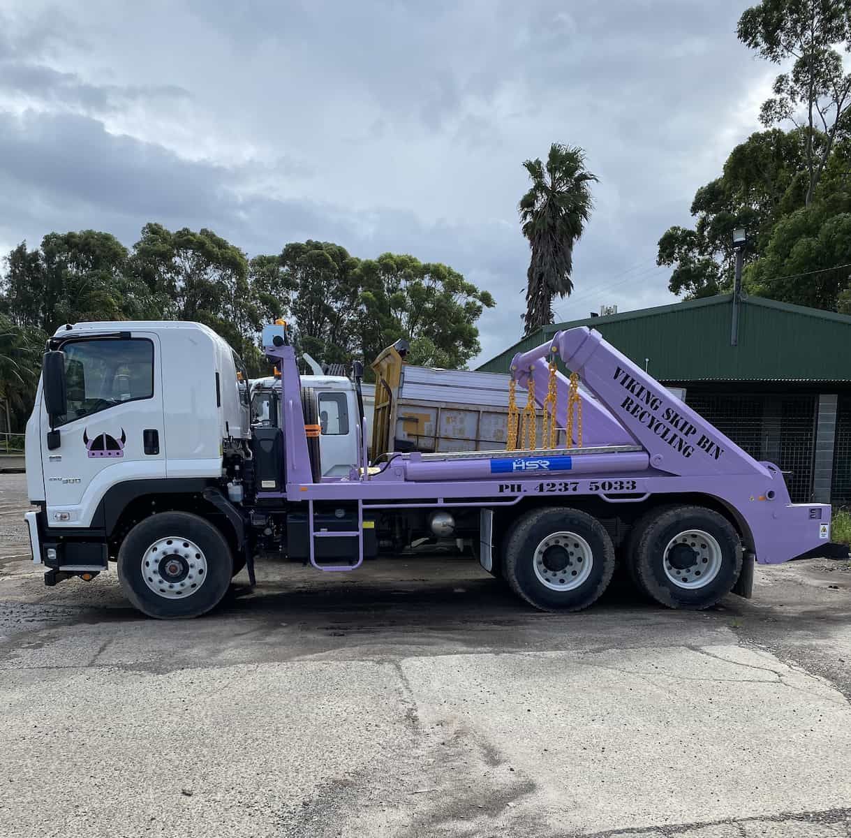 A white and purple dumpster truck is parked on gravel — Viking Skip Bin Recycling In Bomaderry, NSW
