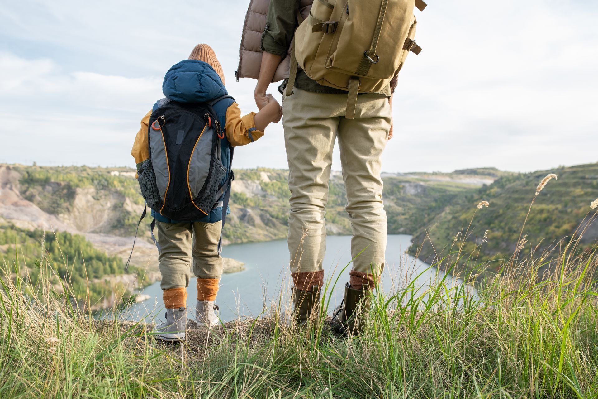 A man with a backpack is standing next to a lake in the woods.