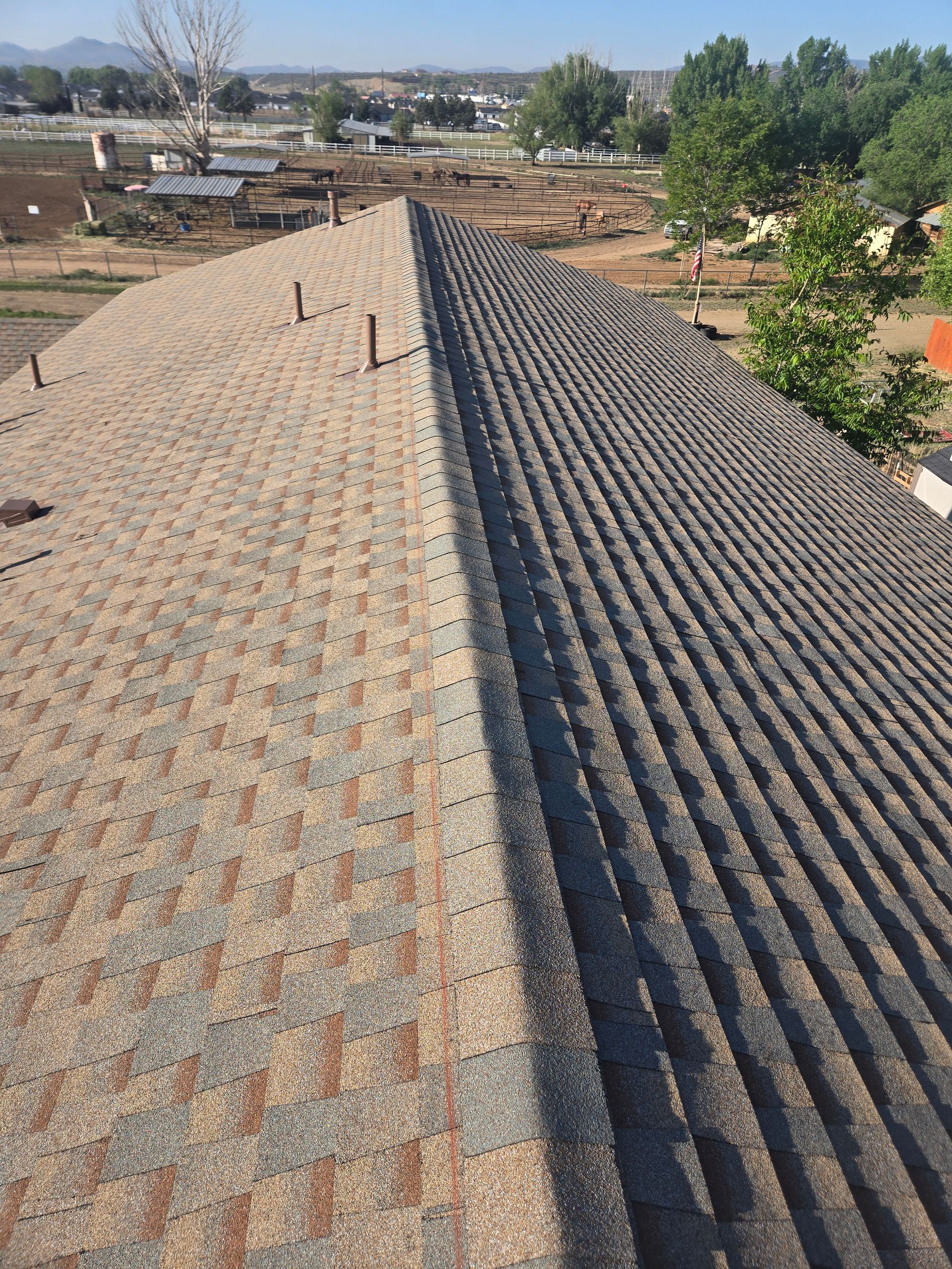 Roof with two different colors of shingles: light brown vs. dark gray. Daytime outdoor setting.