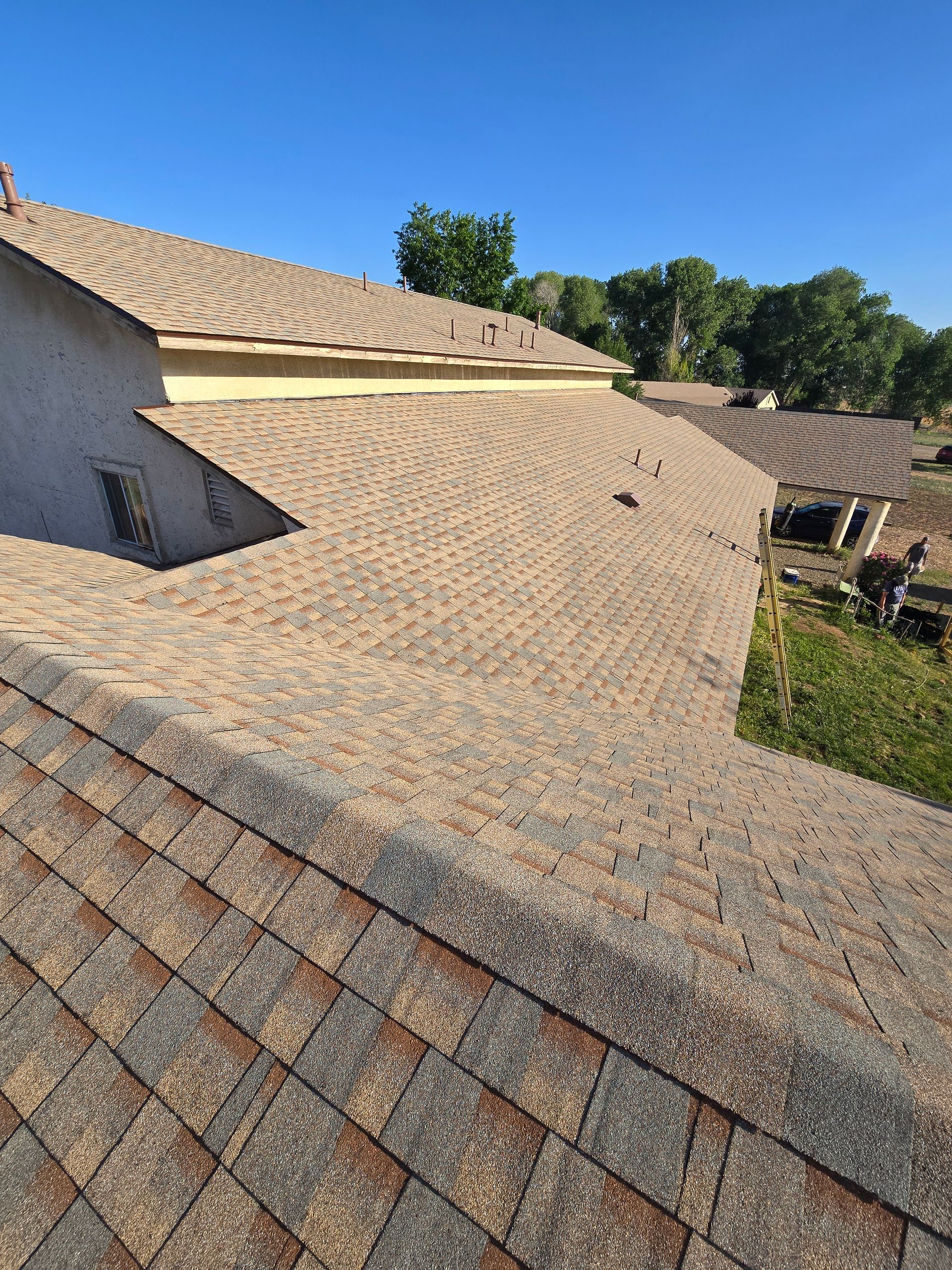 Brown and gray shingled roof with a clear blue sky in the background.