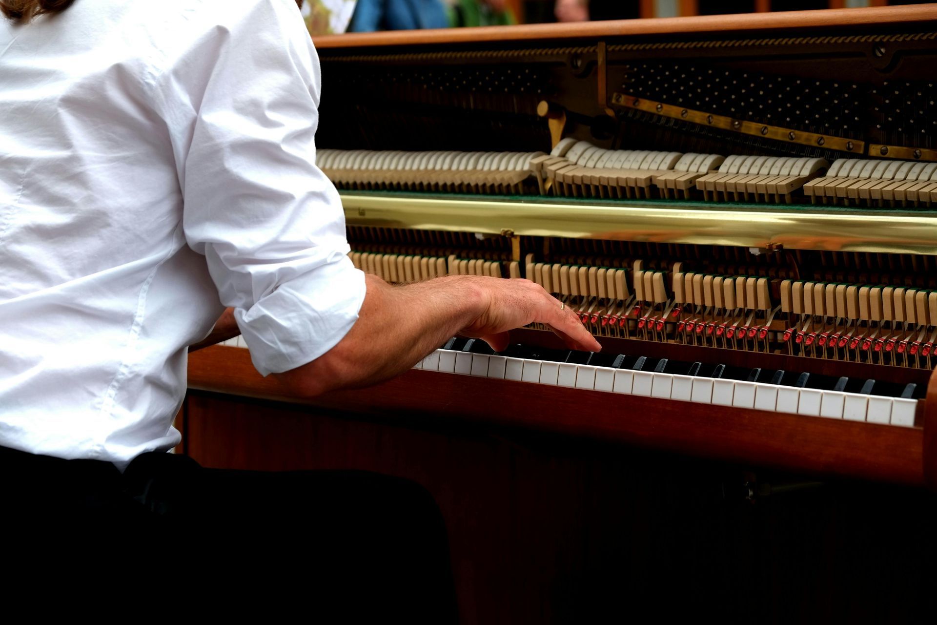 A man in a white shirt is playing a piano