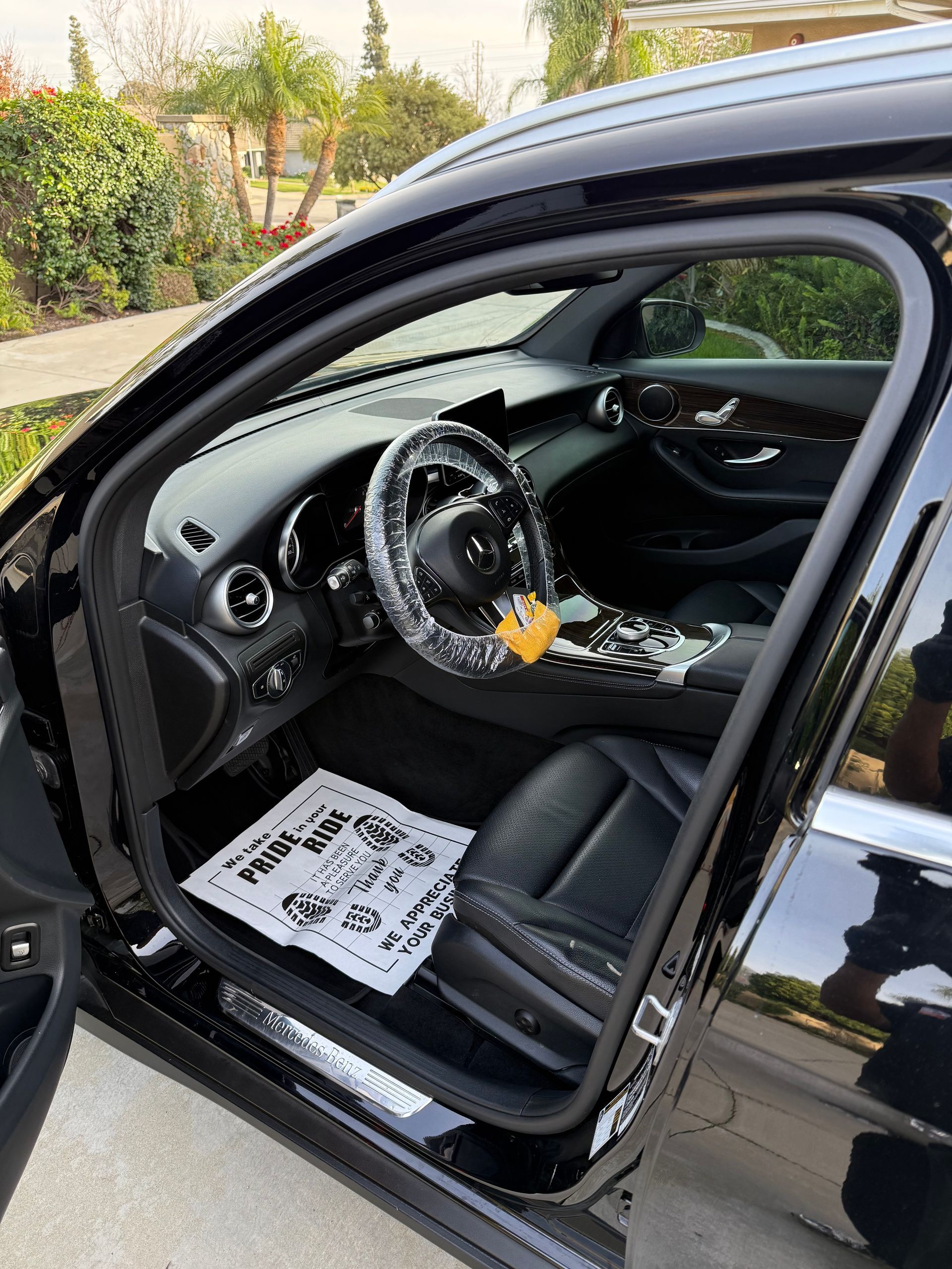 Black car interior with driver door open, showing steering wheel and dashboard.