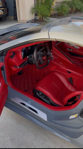 Red sports car interior with bright red seats and steering wheel, viewed from the open door.