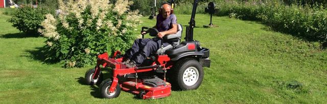 A man is riding a lawn mower on a lush green lawn.