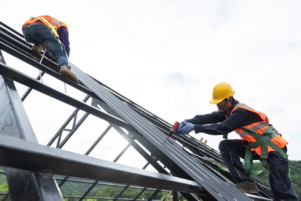 Two Construction Workers Are Working on the Roof of a Building — Coral Coast Roofing In Innisfail, QLD