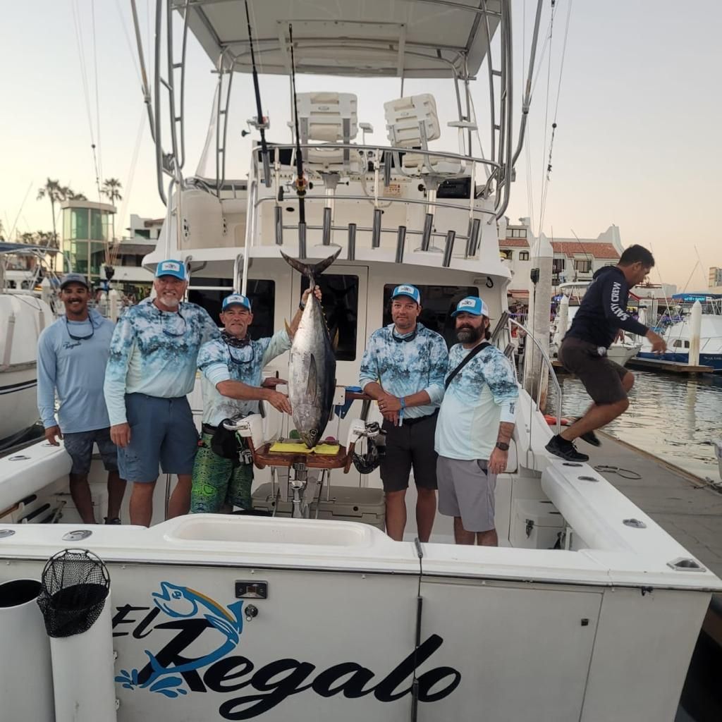 A group of men standing on a boat that says el regalo