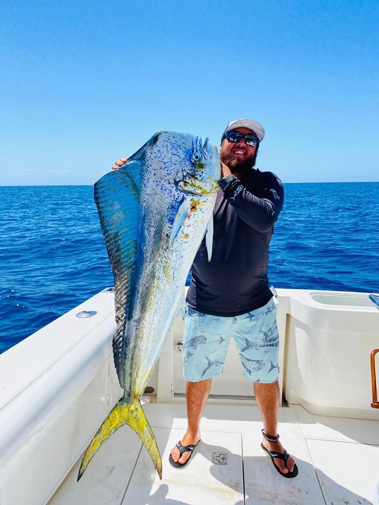 a man is holding a large fish on a boat in the ocean .