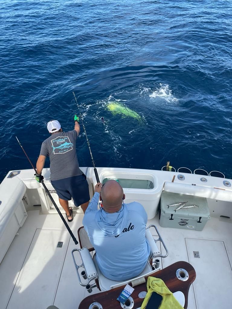 two men are fishing on a boat in the ocean .