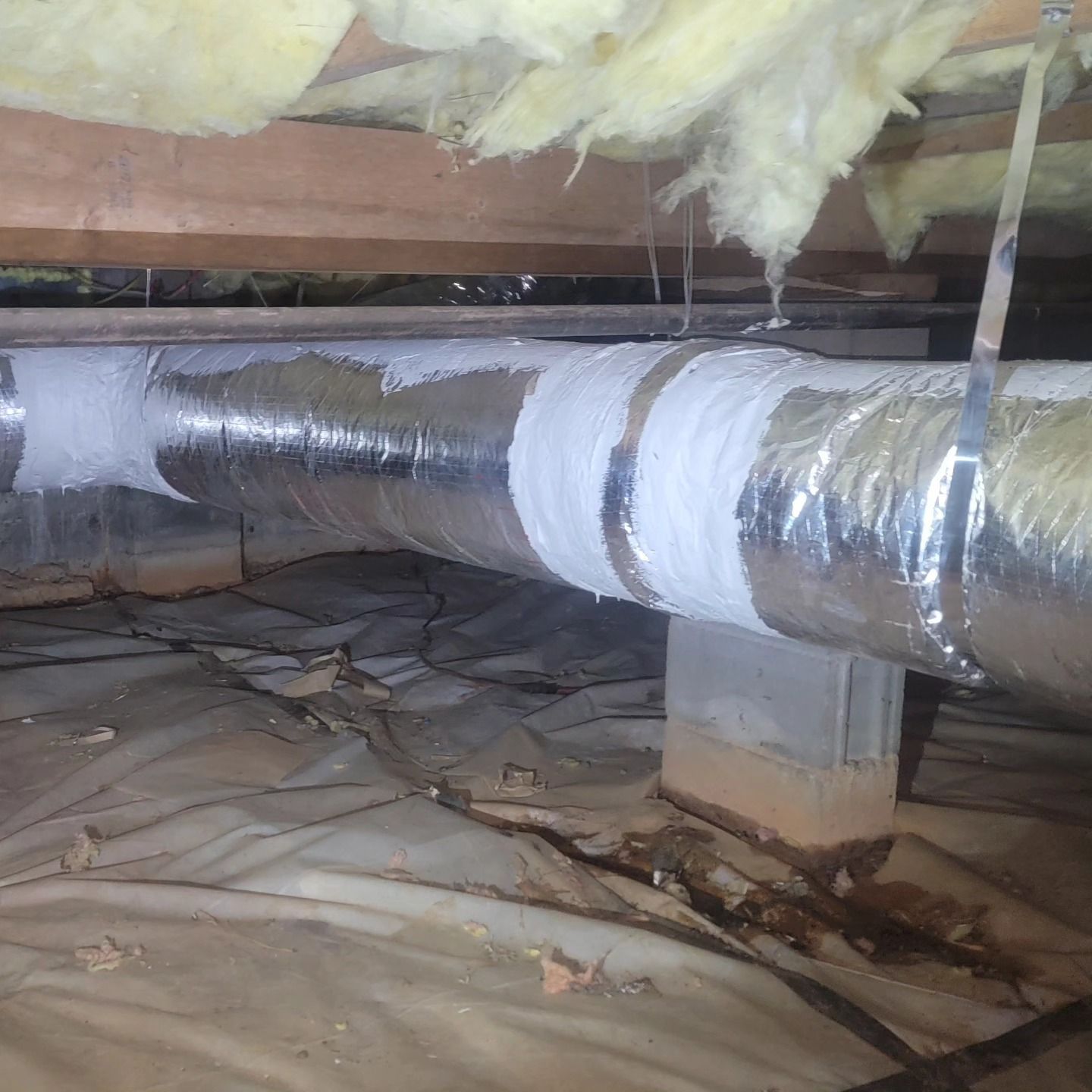 A duct in the ceiling of a house with insulation.
