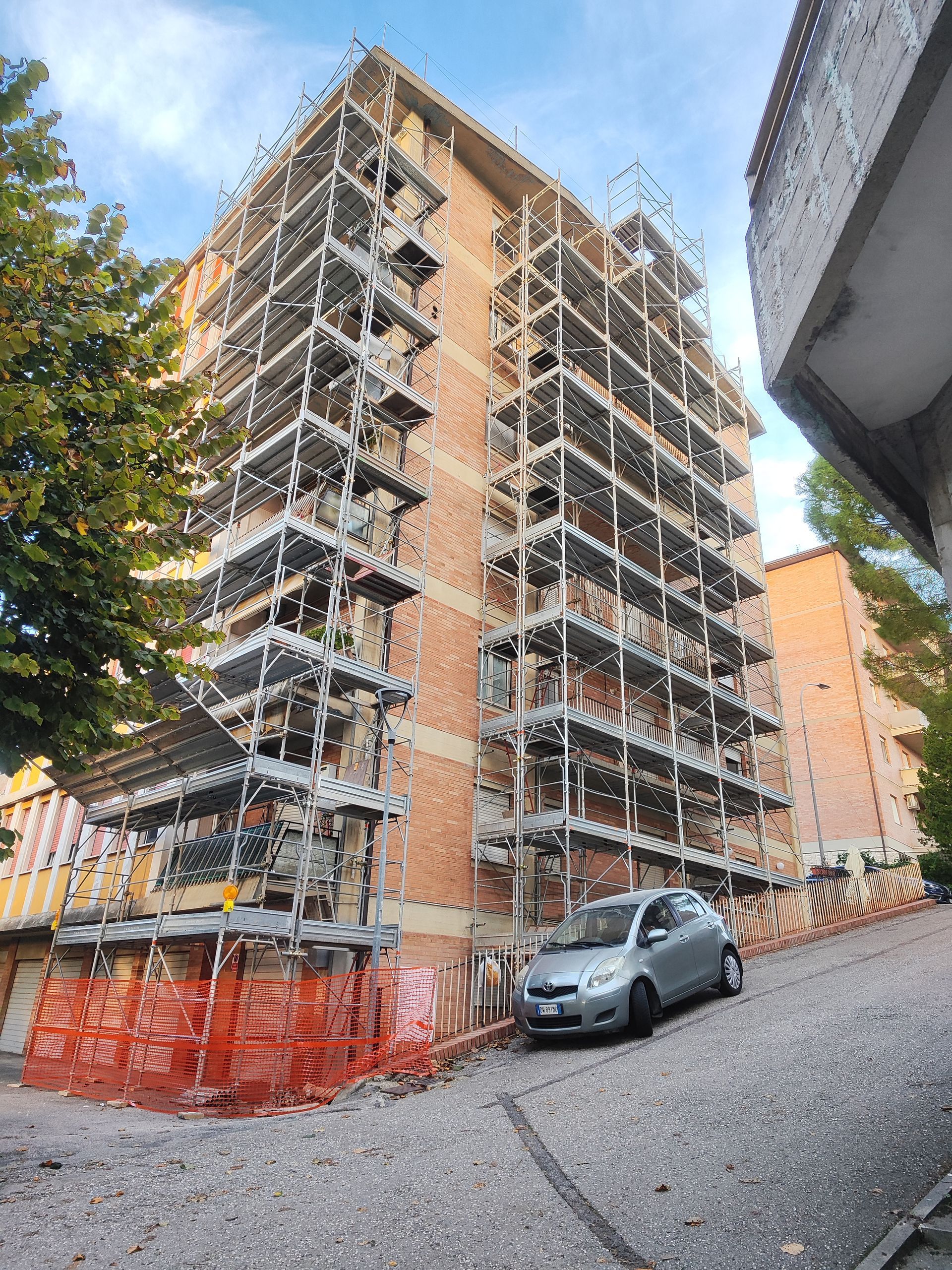Edificio in costruzione con impalcature e un'auto parcheggiata.