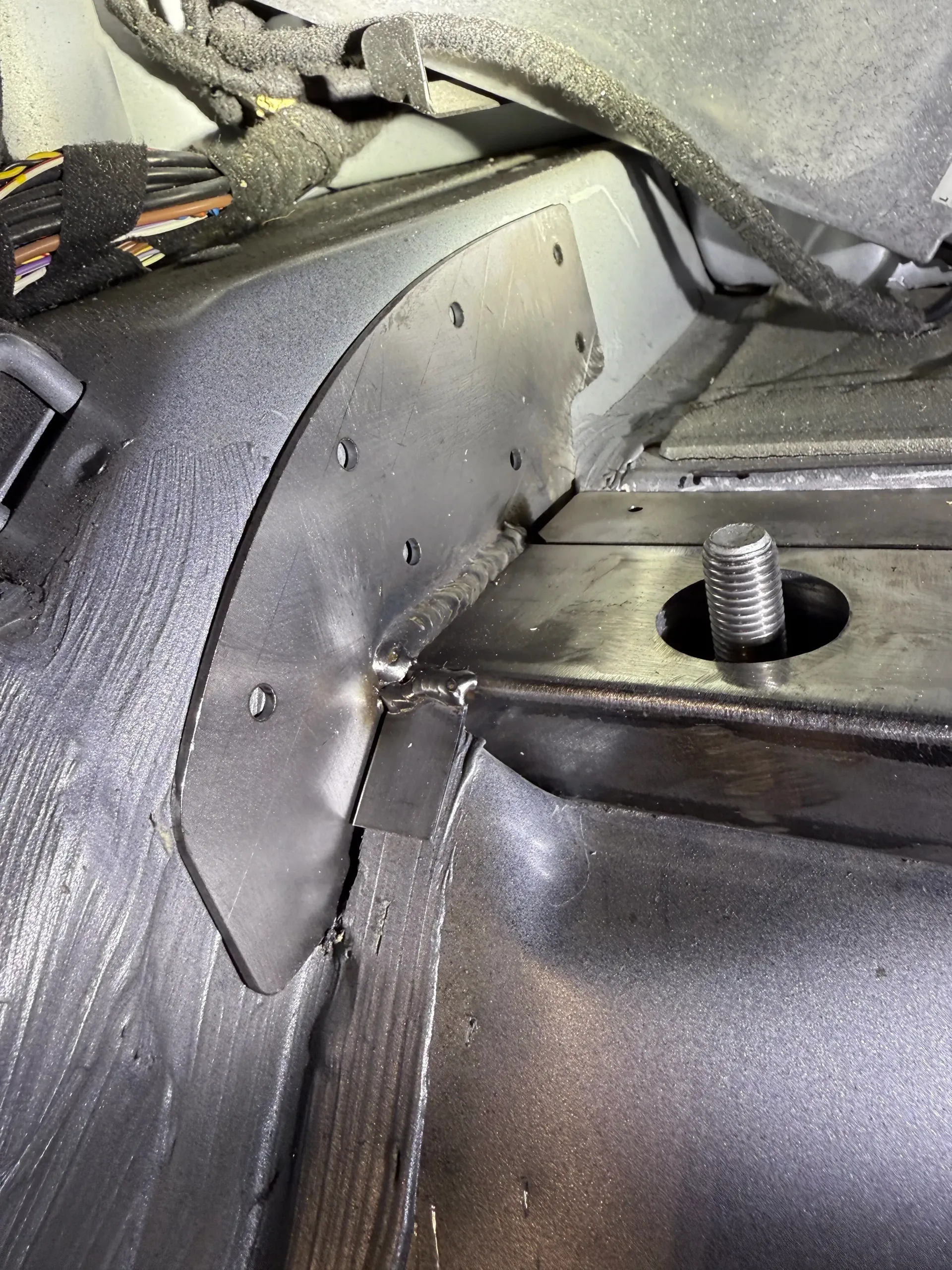 Metal bracket welded to a car's frame, with bolts visible. Black and gray tones. | GermanTech MotorWorks, LLC