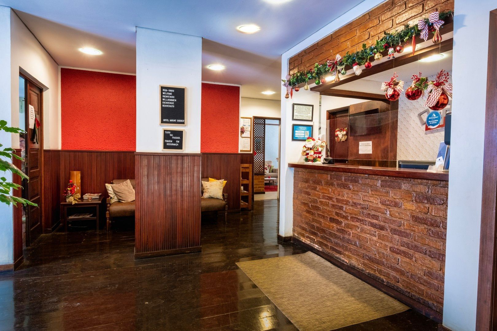 Entrada do restaurante com cabines, painéis de madeira e um balcão de tijolos para a recepção sob luzes aconchegantes.