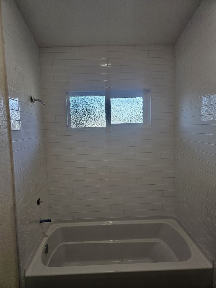 A bathroom with a bathtub and a window.