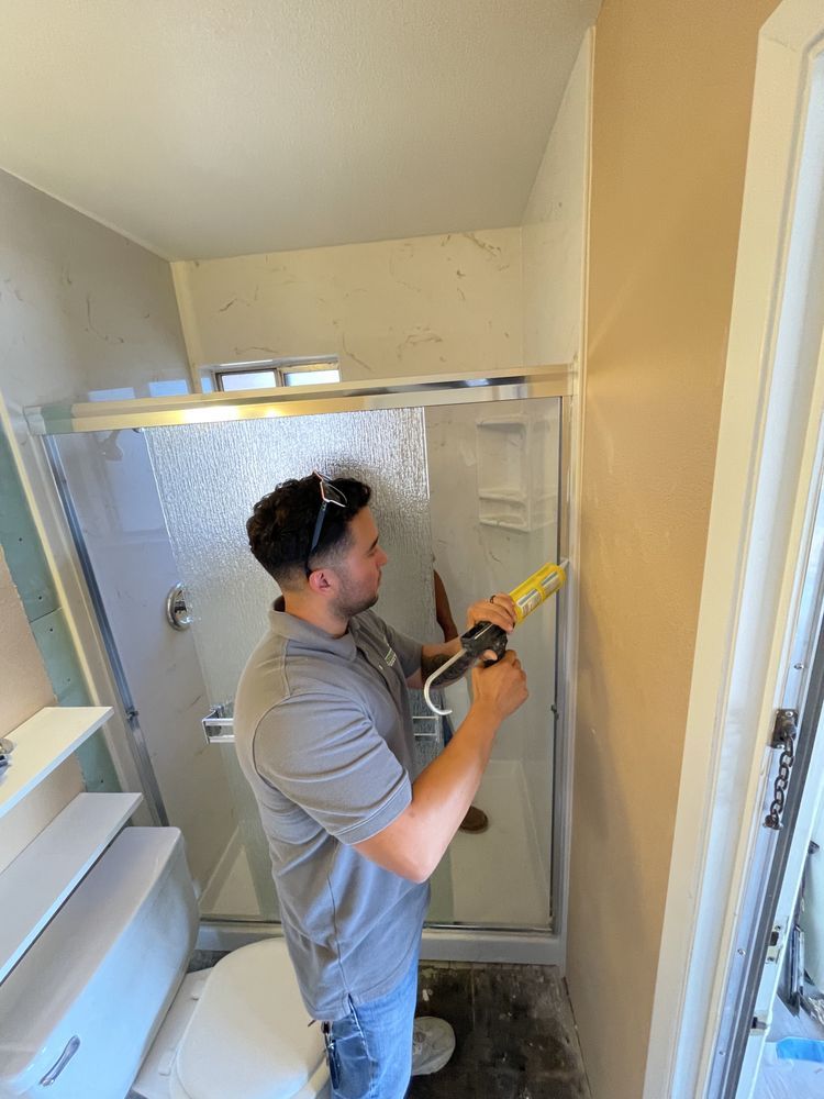 A man is installing a shower door in a bathroom.