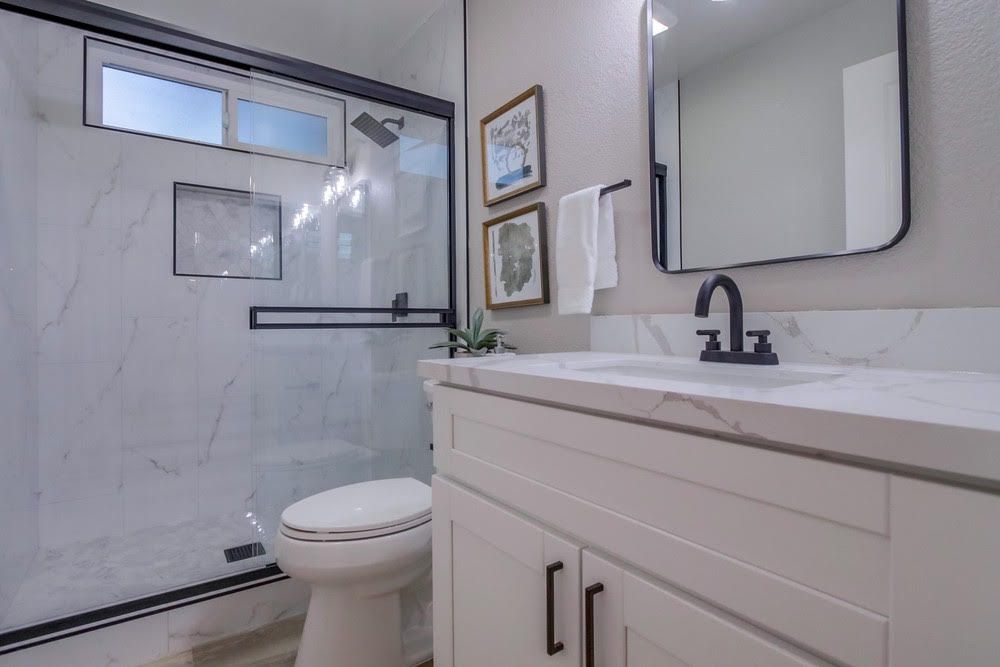 A bathroom with a toilet , sink , mirror and shower.