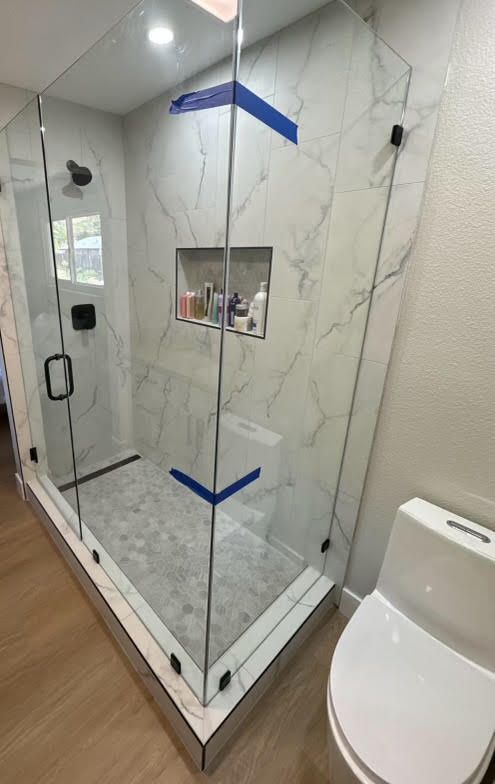 A bathroom with a walk in shower and a toilet.