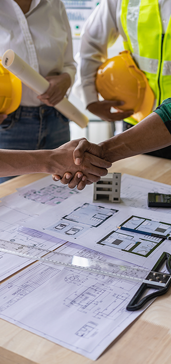 a group of construction workers are shaking hands over a table