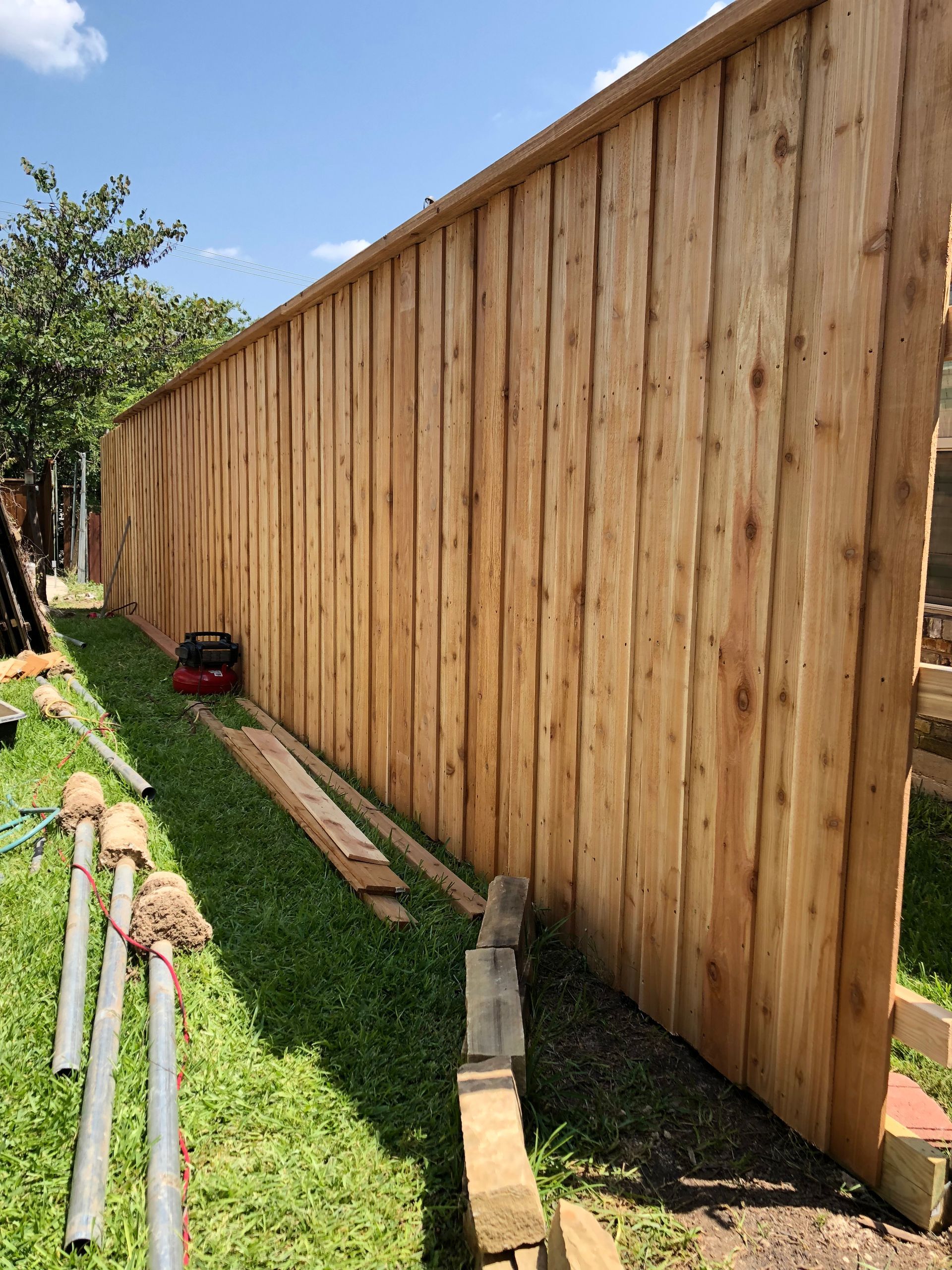 a wooden fence is being built in a backyard