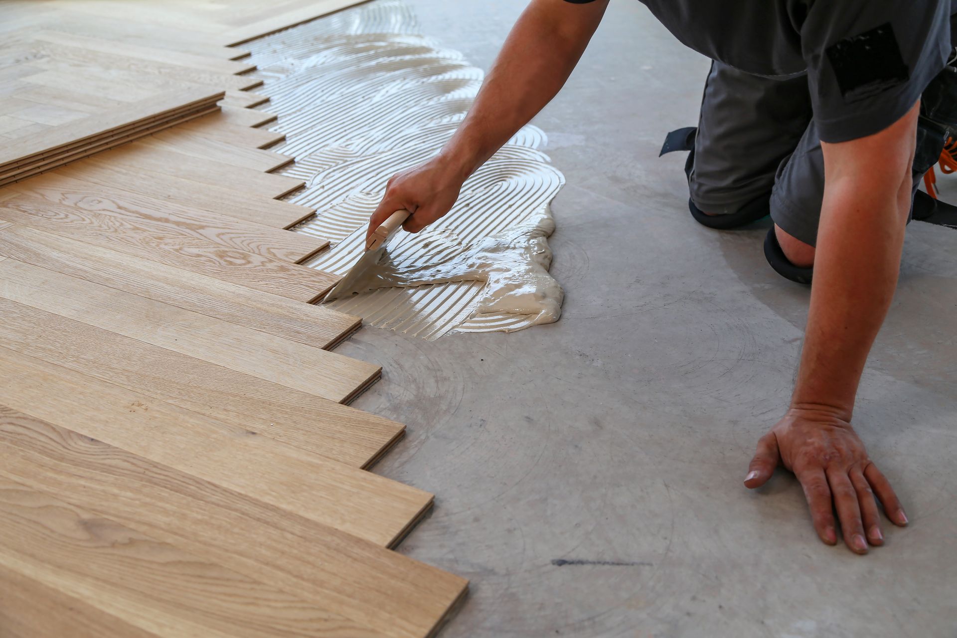 a man is applying glue to a wooden floor