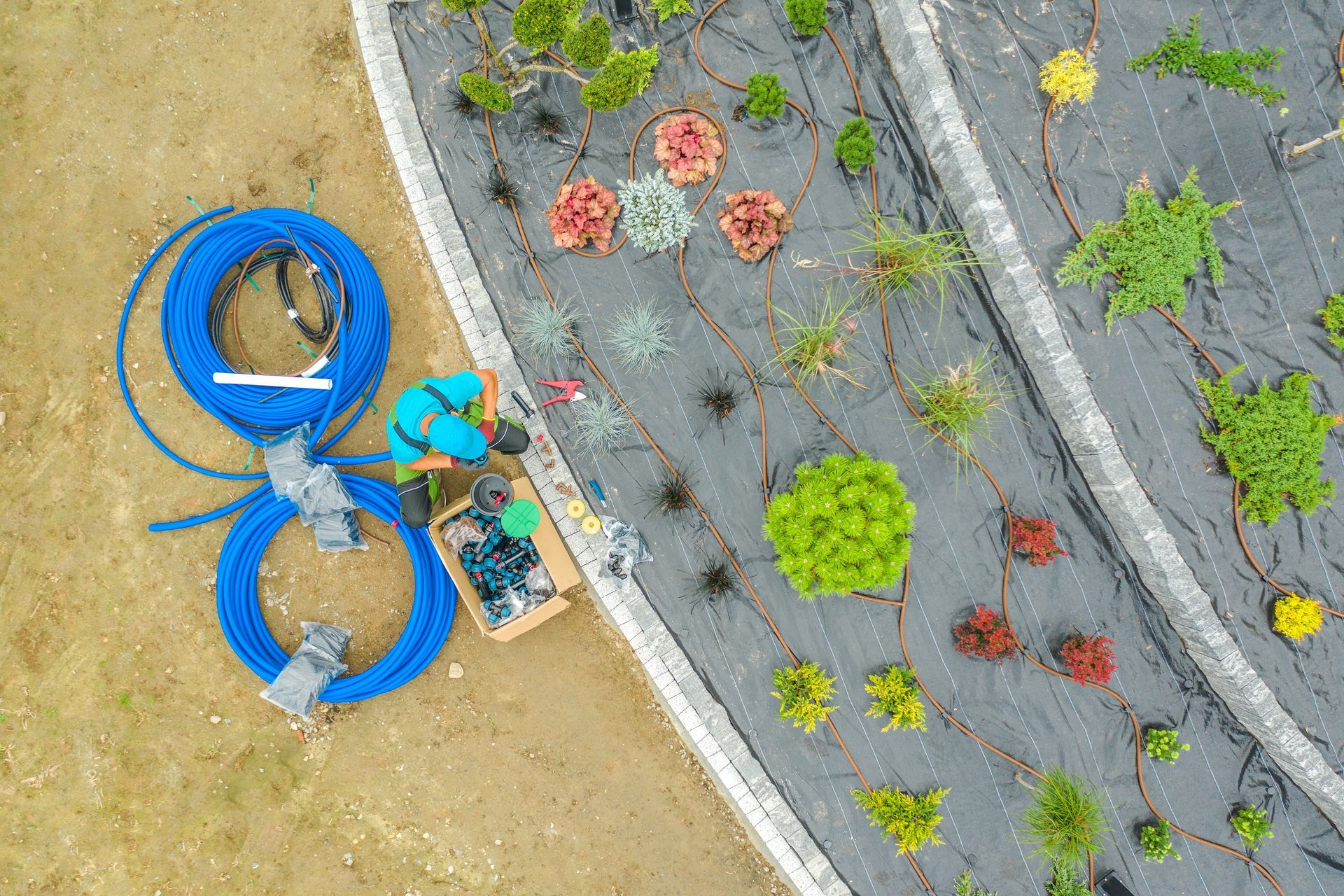 an aerial view of a garden being built with flowers and a hose