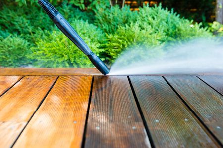 a person is using a high pressure washer to clean a wooden deck