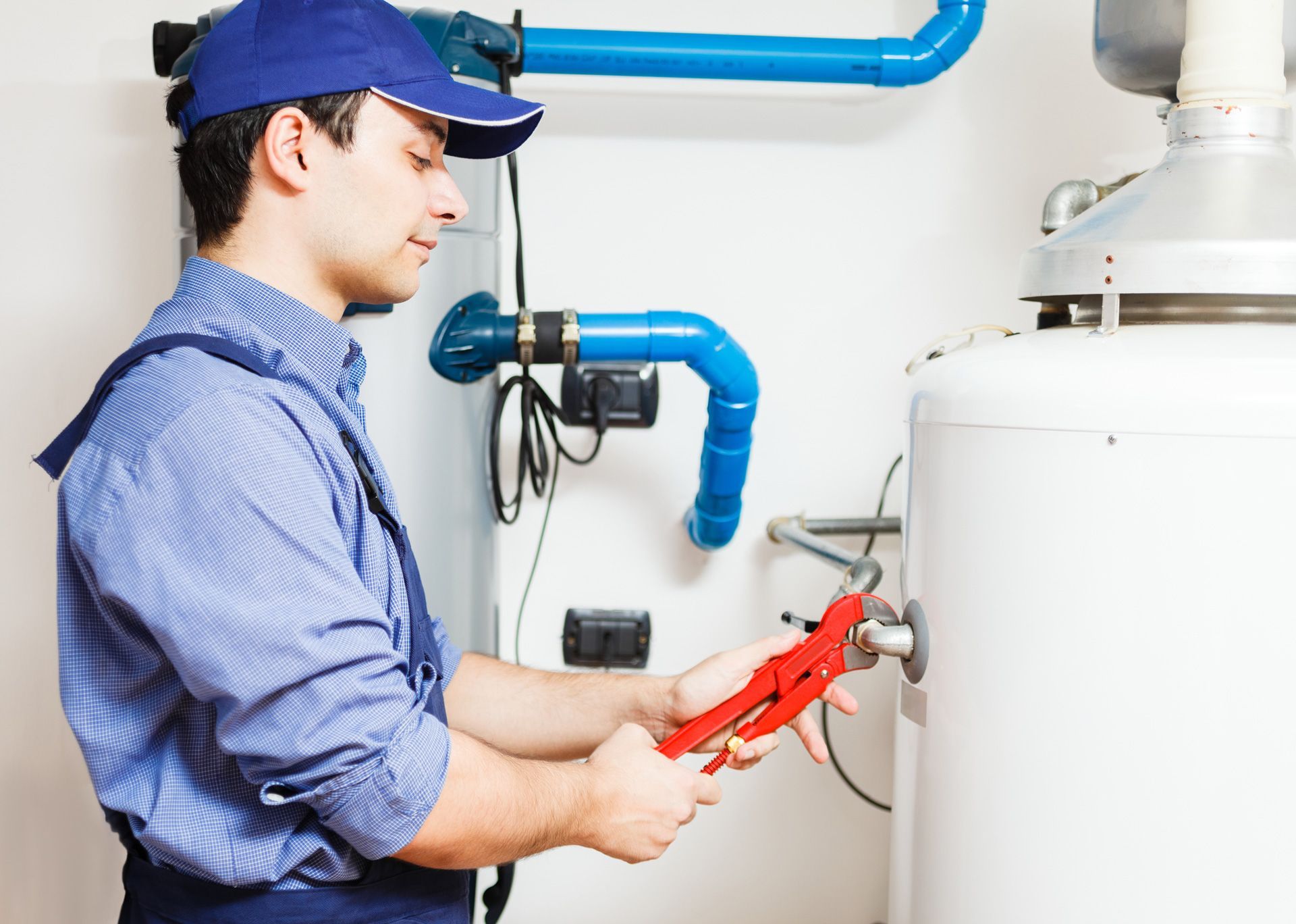 A plumber is fixing a water heater with a wrench.