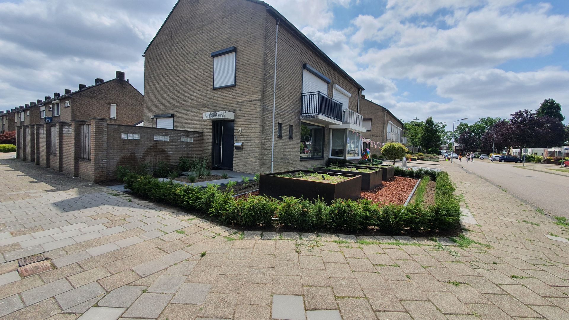 Een woonhuis met een aangelegde voortuin en een bestraat pad.