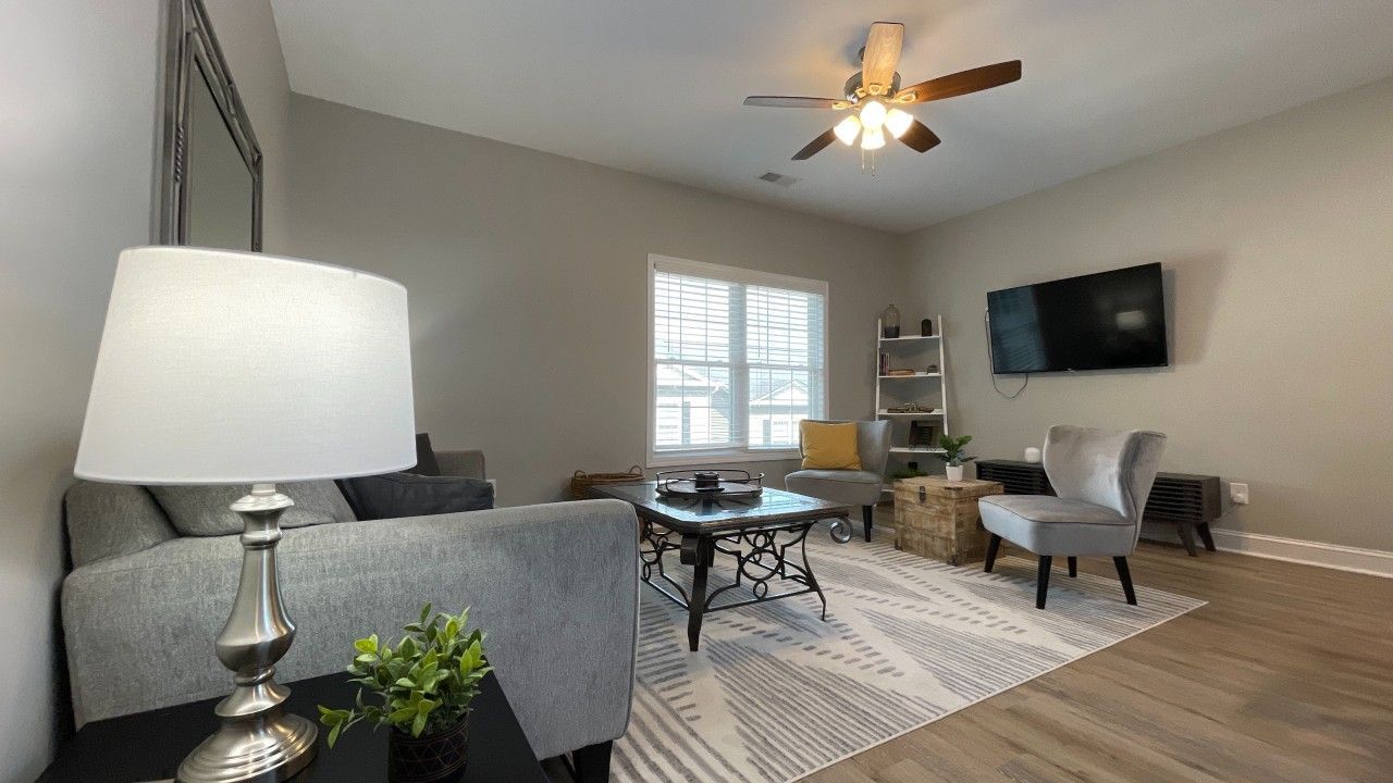 A living room with a couch , chair , table , lamp and television.