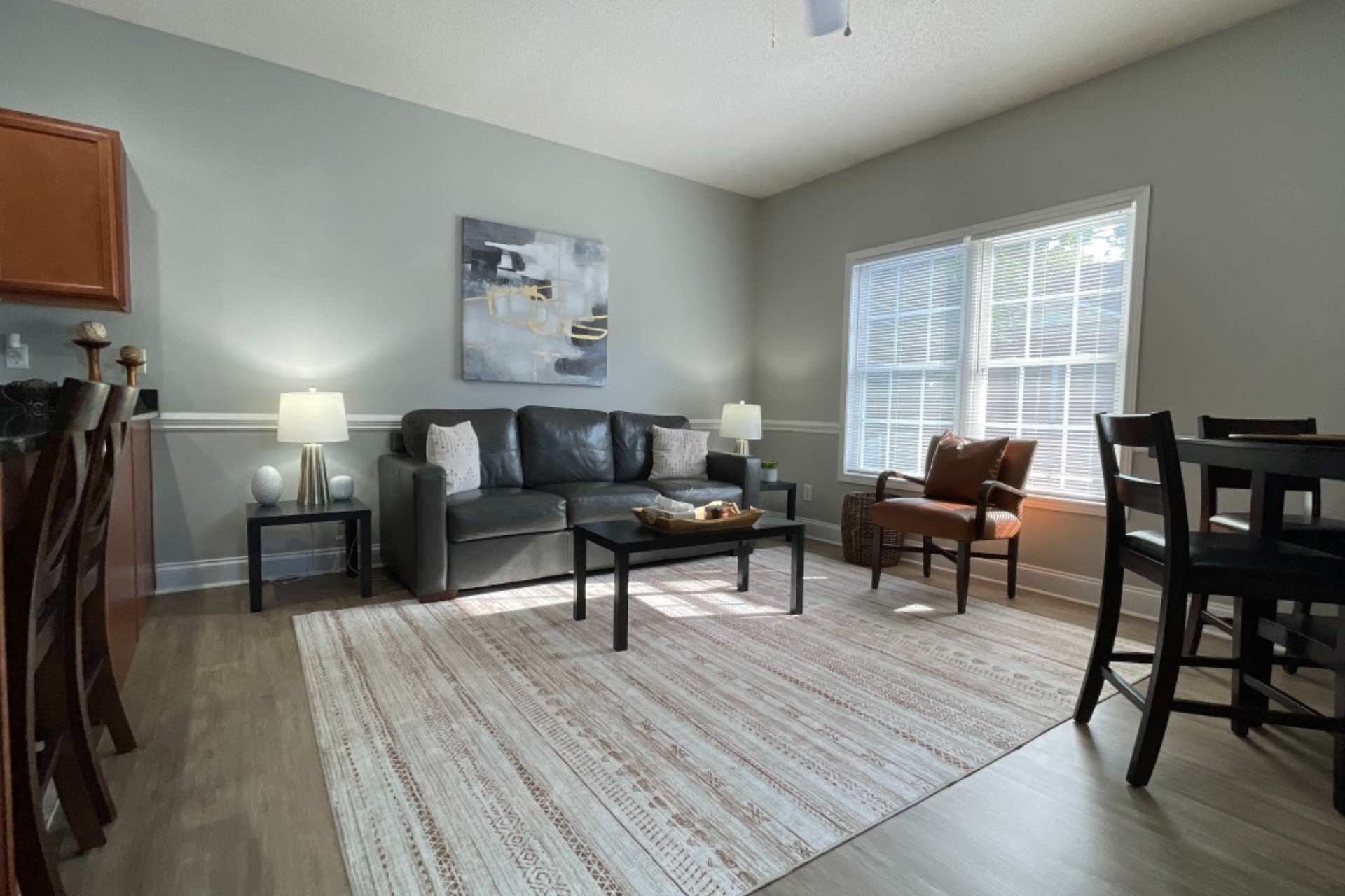 A living room with a couch , chairs , table and rug.