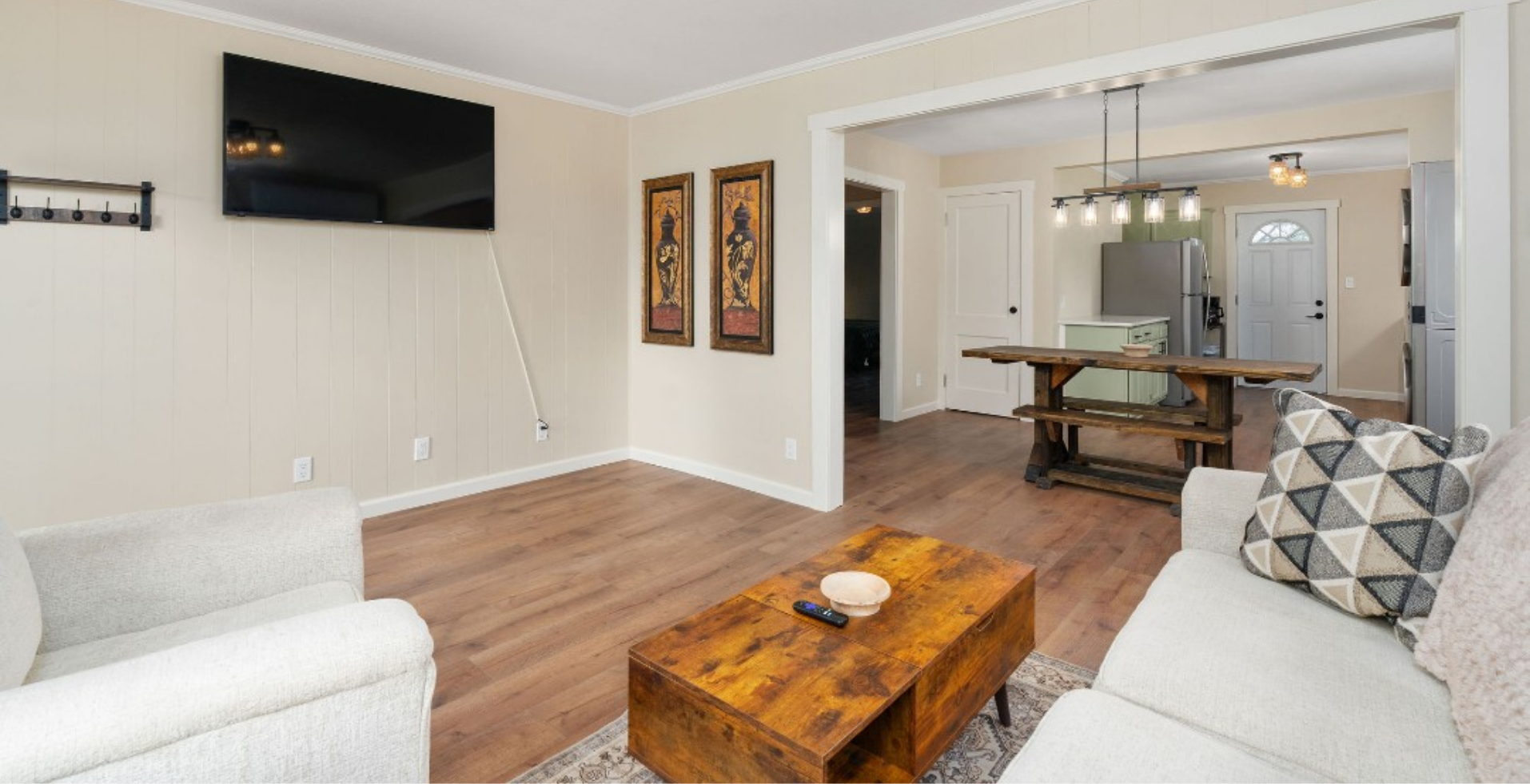 Living room with white sofa, wooden coffee table, TV, and view into dining area.