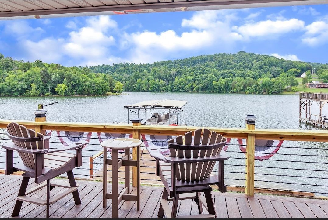 A deck with chairs and a table overlooking a lake