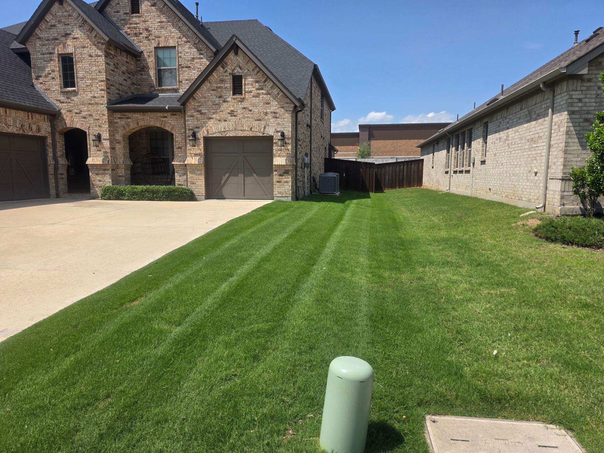 Suburban brick houses with a neatly mowed lawn and driveway on a sunny day