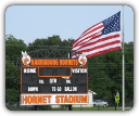 An american flag is flying over a scoreboard for hornet stadium