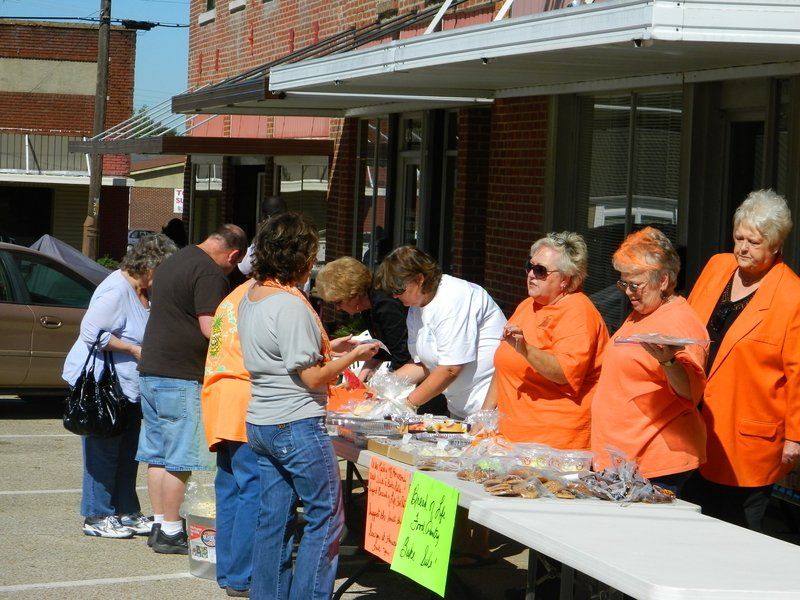A group of people in orange jackets are standing around a table