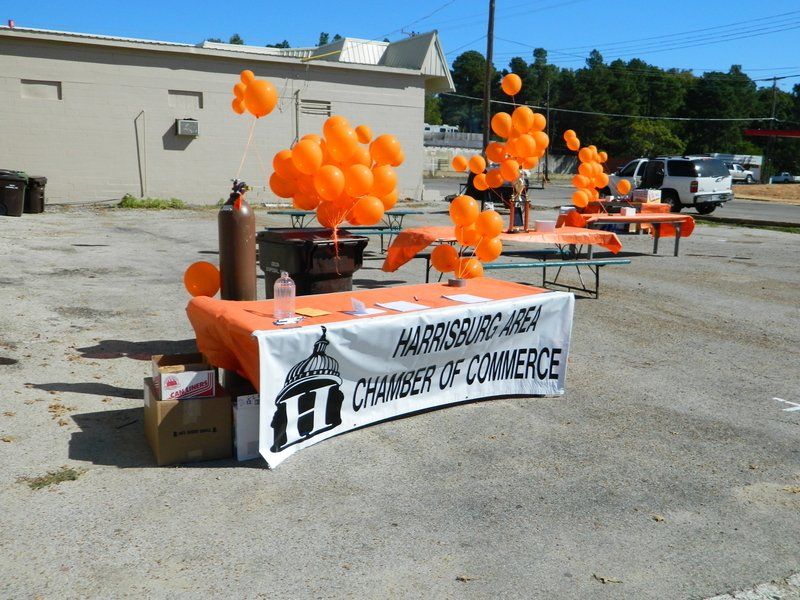 A table with orange balloons and a banner that says chamber of commerce